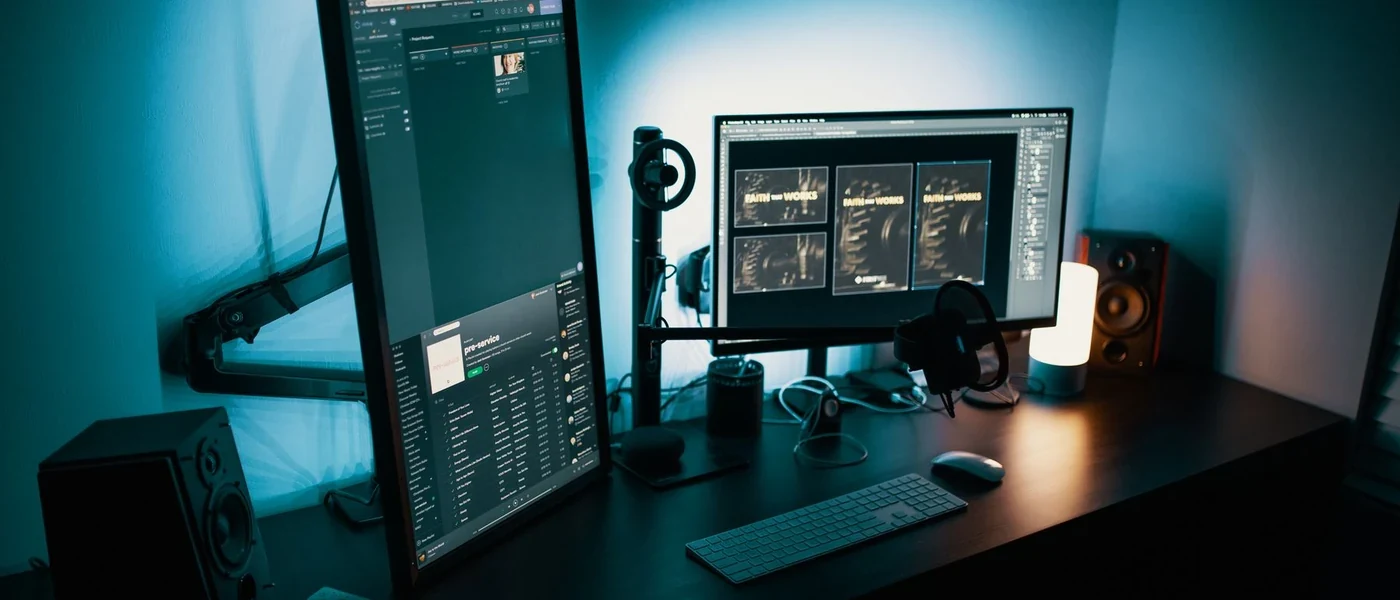 Desk with a portrait and landscape monitor, keyboard and speakers. Not a CS2 screenshot.
